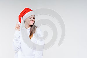 Christmas girl. Beautiful teen model in santa hat  on background