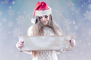 Christmas girl holding an empty wooden board for text.