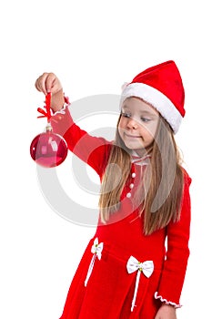 Christmas girl holding and looking at the christmas tree toy in the hand, wearing a santa hat isolated over a white