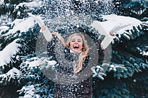 Christmas girl outdoor portrait. Beautiful woman blowing snow in winter forest