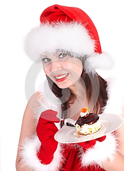 Christmas girl in red santa hat and cake on plate.