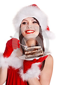 Christmas girl in red santa hat eating cake on plate.