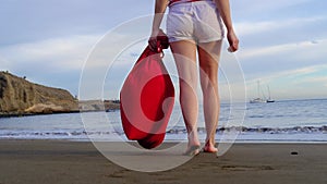 Christmas Girl Santa Claus walking at ocean sandy beach with large red bag full of presents - New Year vacation and