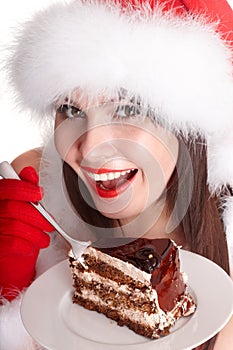 Christmas girl in santa hat and cake on plate.