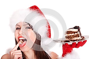 Christmas girl in santa hat eat cake .
