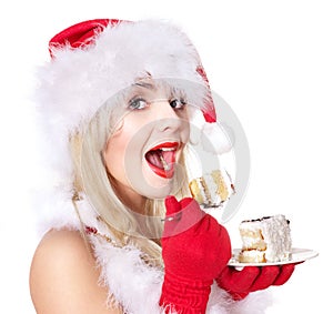 Christmas girl in santa hat eating cake .