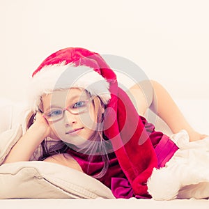 Christmas girl in santa hat lying on sofa