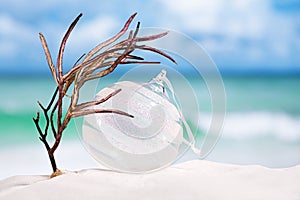 Christmas glass ball on white sand beach with seascape backgrou