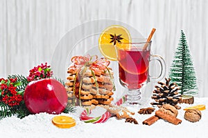 Christmas glass of red mulled wine on table with cinnamon sticks, branches of Christmas tree, snow,