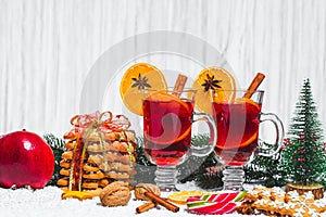 Christmas glass of red mulled wine on table with cinnamon sticks, branches of Christmas tree, snow,