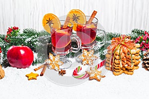 Christmas glass of red mulled wine on table with cinnamon sticks, branches of Christmas tree, snow,