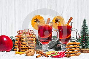 Christmas glass of red mulled wine on table with cinnamon sticks, branches of Christmas tree, snow,