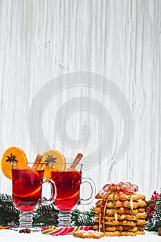 Christmas glass of red mulled wine on table with cinnamon sticks, branches of Christmas tree, snow,