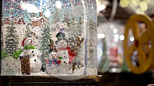 Christmas glass snow globe with a family of snowmen and falling snow from glitter. Slow motion