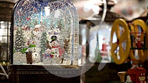 Christmas glass snow globe with a family of snowmen and falling snow from glitter. Slow motion