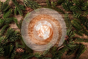 Christmas glowing ball on wooden background with fir branches, spruce, juniper, fir, larch, pine cones