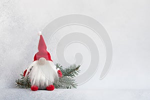 Christmas gnome in red hat with fir branch holiday card on light winter background