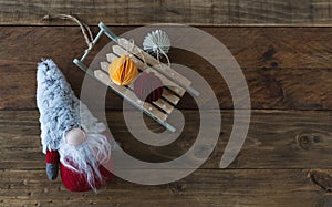 Christmas gnome with sleigh and paper spheres. Wooden background. Copy space