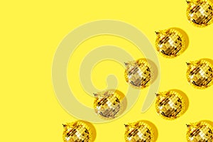 Christmas gold baubles organized on yellow background. Top view. Flat lay. Creative New year pattern. Party time concept. Banner