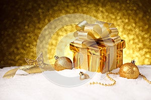 Christmas gold gift box with balls and decoration on snow