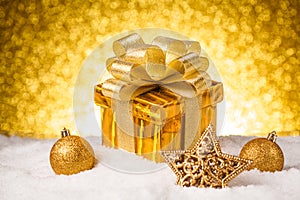 Christmas gold gift box with balls and decoration on snow