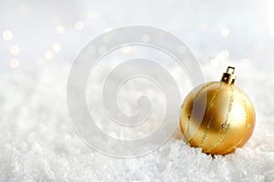 Christmas golden ball on snow abstract background with lights