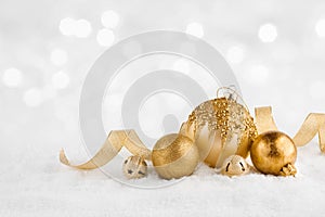 Christmas golden balls on snow over abstract winter lights background