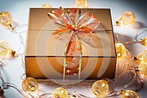 Christmas a golden gift box with a red bow and a beautiful glowing garland against