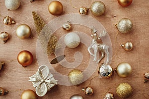 Christmas golden glitter tree, reindeer , gift box and shiny baubles and balls on rustic background, flat lay. Modern gold