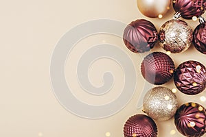 Christmas golden and purple glitter bauble balls on neutral background with copy space. Top view, flat lay