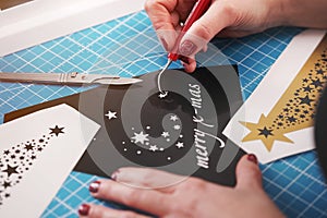 christmas graphic cut from black adhesive foil is finished by female hands with painted nails.