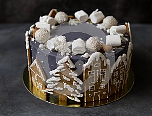 Christmas gray cake decoraited of gingerbread cookies in shape of homes and snowy christmas trees, marshmallows