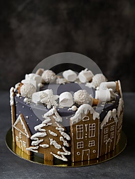 Christmas gray cake decoraited of gingerbread cookies in shape of homes and snowy christmas trees, marshmallows