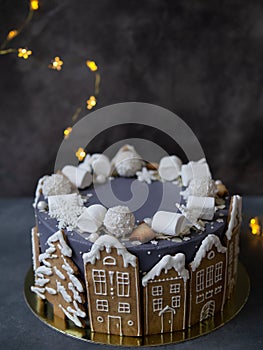 Christmas gray cake decoraited of gingerbread cookies in shape of homes and snowy christmas trees, marshmallows, snowflakes,