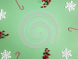 Christmas green background with snowflakes, candy canes and red berries