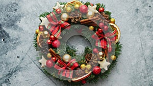 Christmas green, red and golden wreath with decorations isolated on stone background