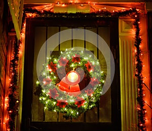 Christmas green wreath with red bells on the front door. Entrance to the house decorated for the winter holiday - Xmas and New