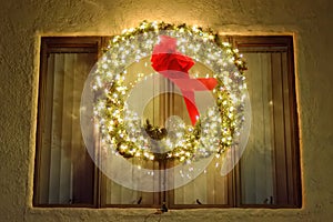 Christmas green wreath with red ribbon on the front door. Entrance to the house decorated for the winter holiday - Xmas and New