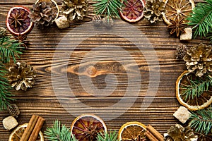 Christmas greeting card backgroun. Dried oranges, spice, fir tree branches frame on wooden brown table background. Copy-space