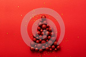 Christmas greeting card with Christmas tree made of red toys balls decorated golden confetti in red envelope on red background. Ne