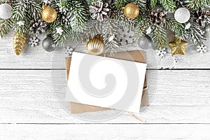 Christmas greeting card with fir tree, golden and silver decorations on white wood background. Flat lay
