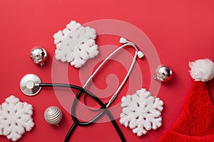 Christmas greeting card for medics. Traditional Christmas and New Year decorations and medical stethoscope on red background