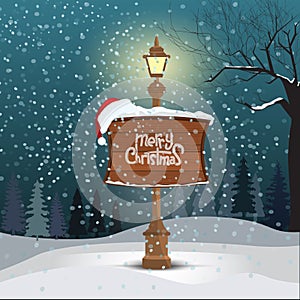 Christmas greeting card - snowy winter landscape background. Street lamp and wood board with merry christmas calligraphy