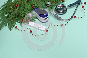 Christmas greeting card. stethoscope, pulse oximeter, rapid test and Christmas decorations on green background, Medical