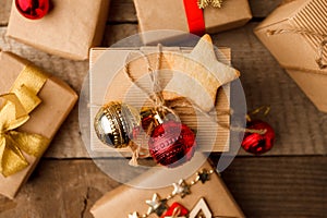 Christmas handmade gift boxes decorated with craft paper and red gold balls and handmade cookie star on vintage wooden background
