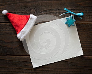 Christmas and Hannukah blank Happy Holidays Card on Rustic Boards with white paper, a Santa hat and Hanukah decoration.