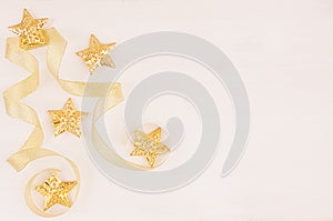 Christmas happy background, gold stars, curl ribbons on soft white wood board, copy space, top view.