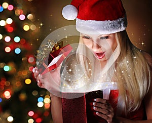 Christmas. Happy Blonde Girl with Santa Hat Opening Gift Box