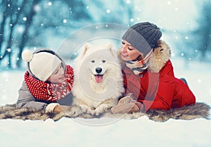 Christmas happy family, mother and son child walking with white Samoyed dog, lying on snow in winter day