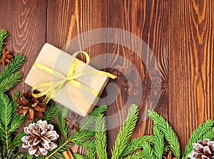 Christmas and Happy New Year dark brown background. Gift Christmas box, fir branches, wooden table, top view, copy space